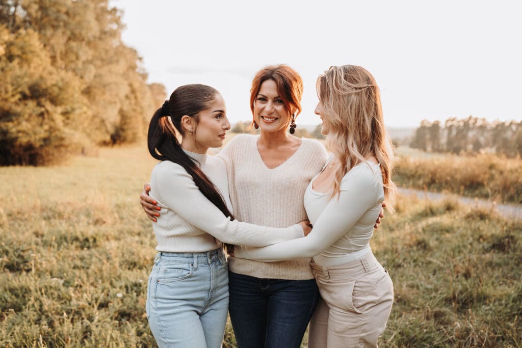 Mutter kuschelt mit ihren Töchtern bei Sonnenuntergang während eines Familienfotoshootings in Nagold