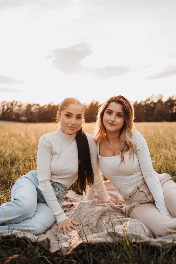 Schwestern sitzen gemeinsam bei Sonnenuntergang während eines Familienfotoshootings in Nagold